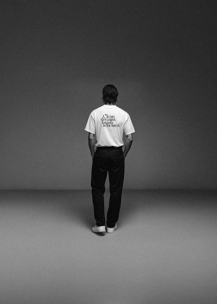 Person wearing a white t-shirt with text on the back, standing against a plain gray background