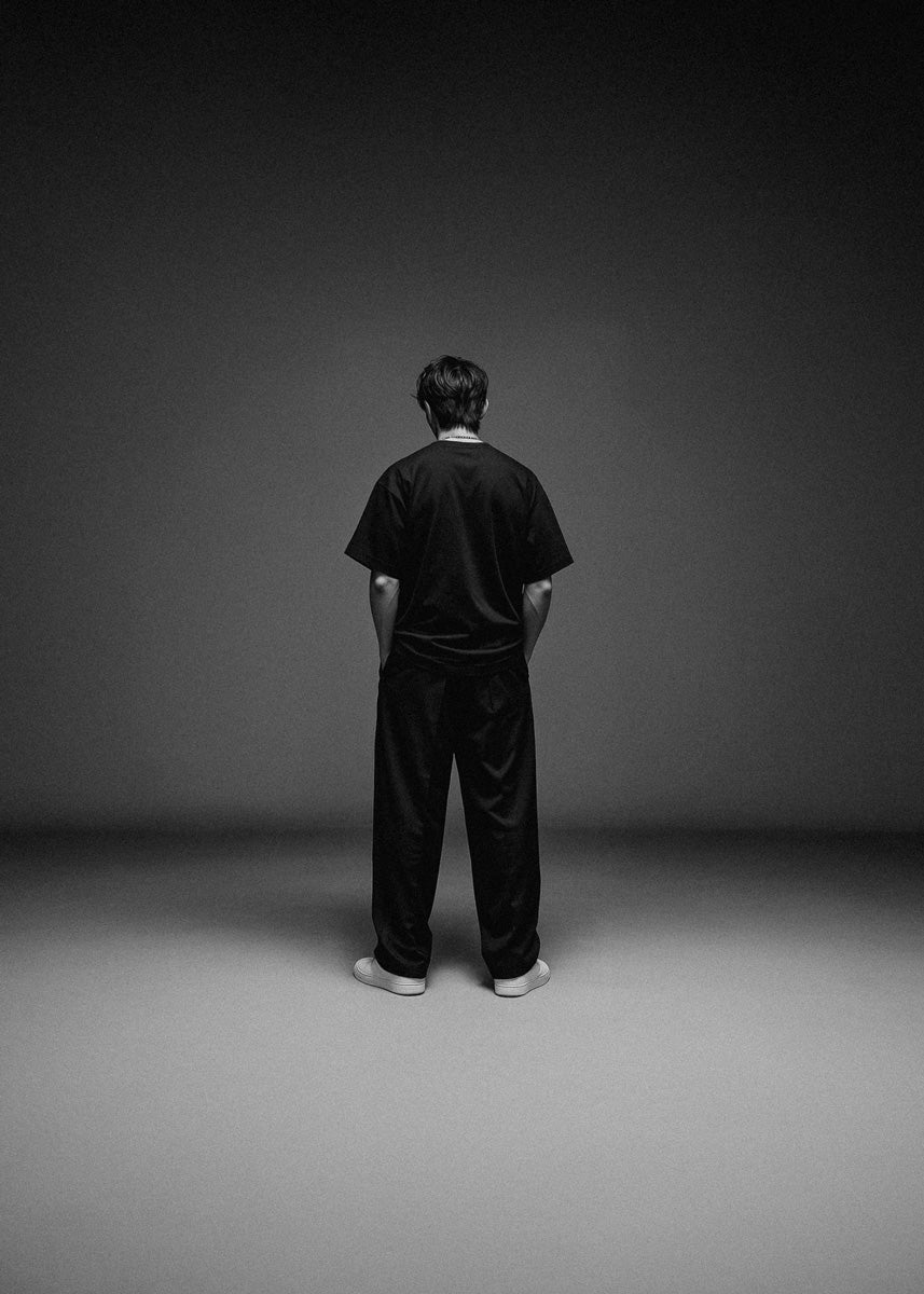 Person wearing a black outfit standing against a dark background