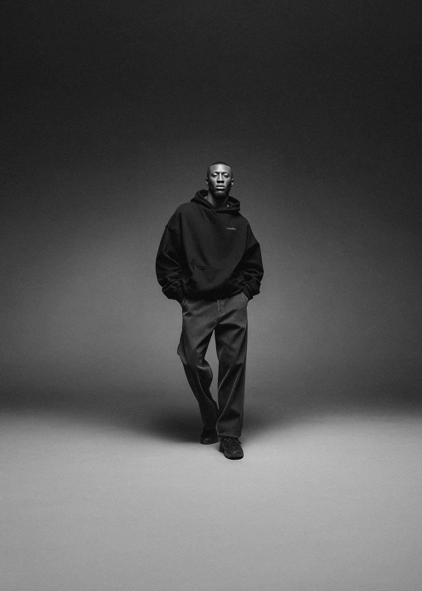 Person wearing a black hoodie and pants on a gray background