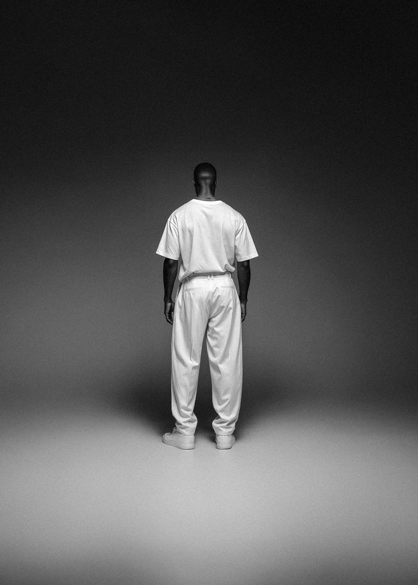 Person wearing a white outfit standing against a dark background